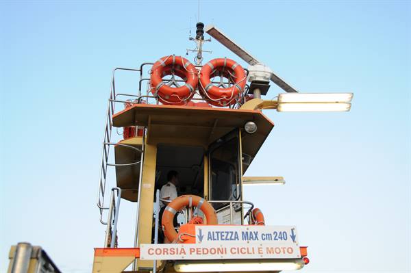 Ferry wheelhouse with orange lifebuoys and sign for pedestrians bicycles and motorcycles