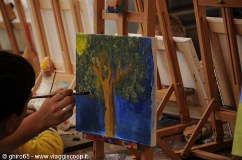 Hand with brush painting a tree on canvas, wooden easels, natural light