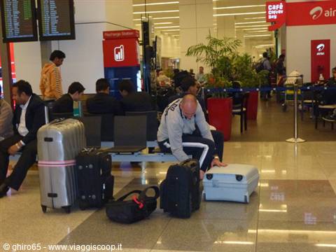Man arranging suitcases in an airport waiting area