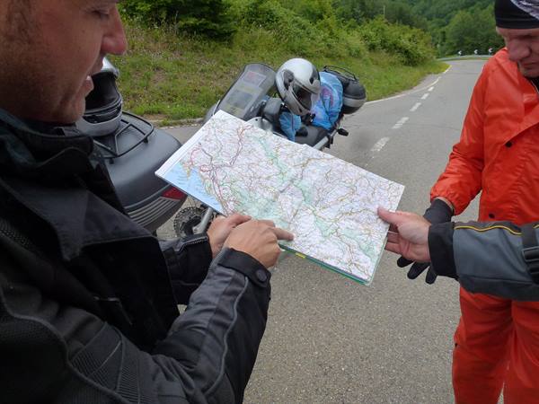 Two motorcyclists check a paper road map beside their parked bikes