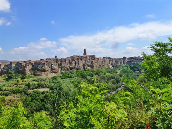 Pitigliano, tuff stone houses perched on the cliff under blue sky
