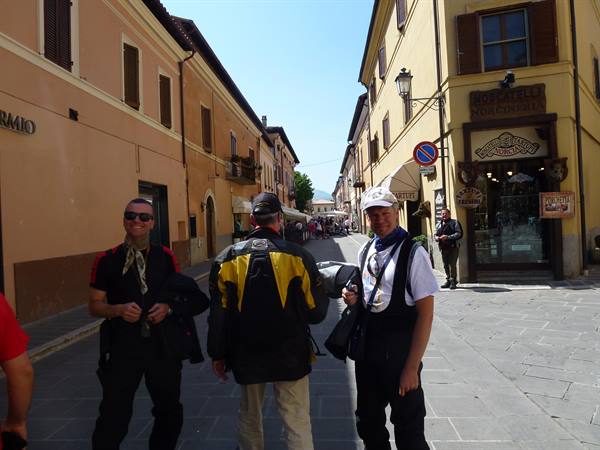 Three motorcyclists in gear on a paved street lined with colorful buildings
