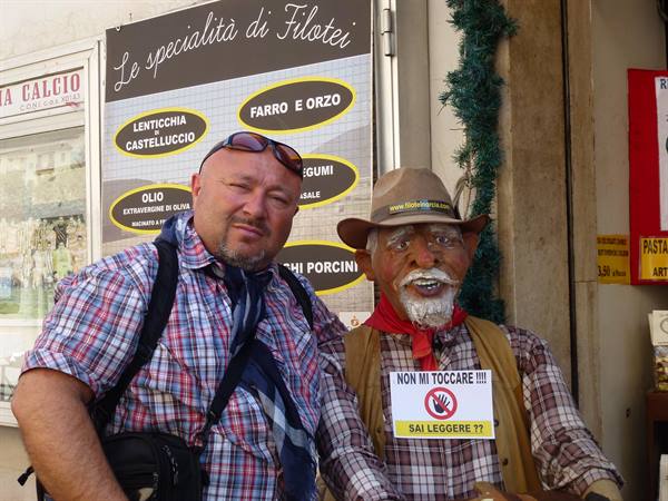 Man posing beside a cowboy statue outside the Le specialità di Filotei shop