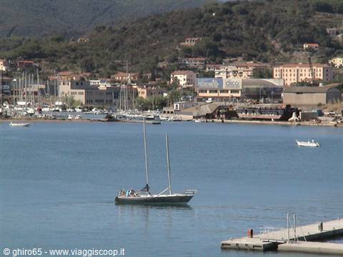Sailboat floating in the bay near the marina and hillside buildings