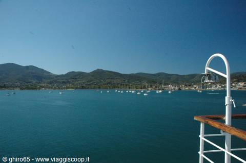 Anchored boats in a turquoise bay with green hills, seen from the ship