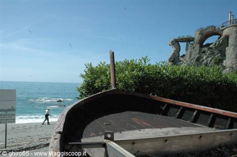 Wooden boat on Monterosso beach, rocky cliff and swimmer in background