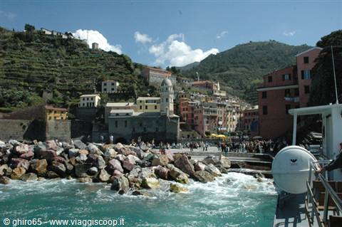 Vernazza seen from the sea: colorful houses on the cliff and rock breakwater