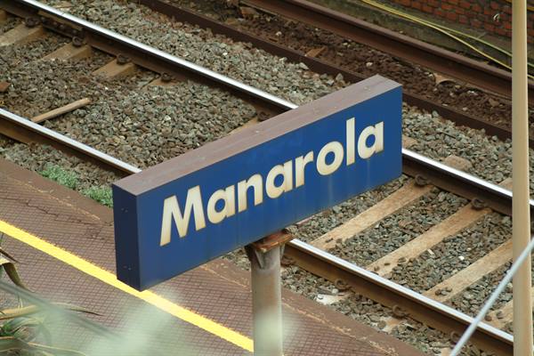 Blue Manarola station sign beside railway tracks