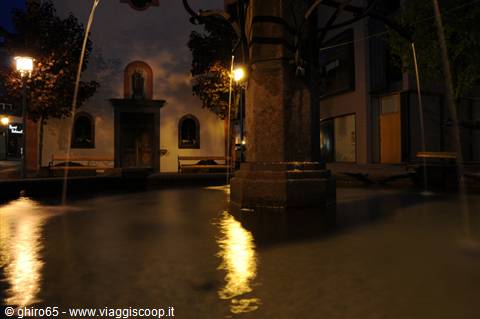 Stone fountain at night with water jets and reflected lights