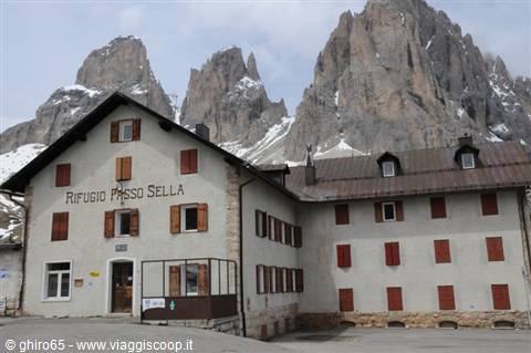 Rifugio Passo Sella, white facade with red shutters beneath snowy Dolomite peaks