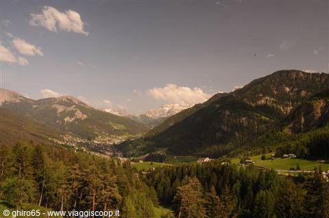 Village in a valley with snowy Dolomite peaks and green meadows