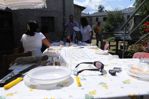 Lunch table in a courtyard, sunglasses and plates, people gathered in the sun