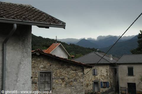 Stone houses and rooftops beneath cloudy mountain peaks