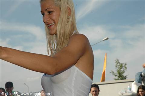 Blonde woman in wet white top smiling among an outdoor crowd