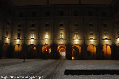 Illuminated arcaded facade at night over a snowy courtyard, likely Palazzo Carignano, Turin