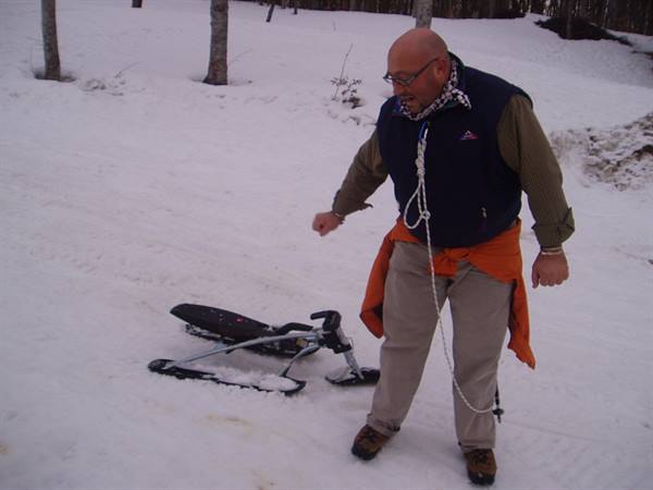 Man with a snow sled among snowy trees