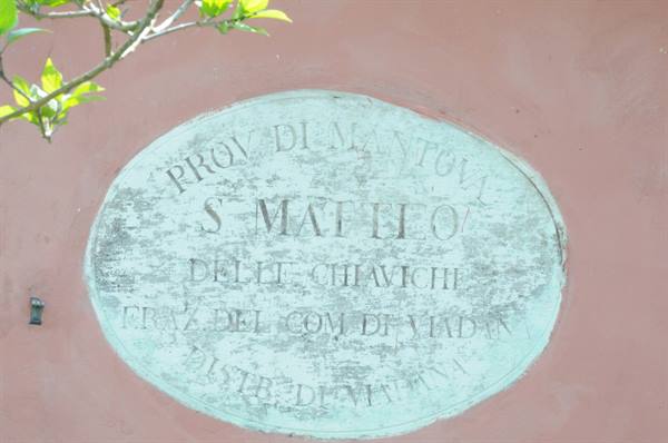 Oval marble plaque of San Matteo delle Chiaviche, Viadana hamlet, on pink wall