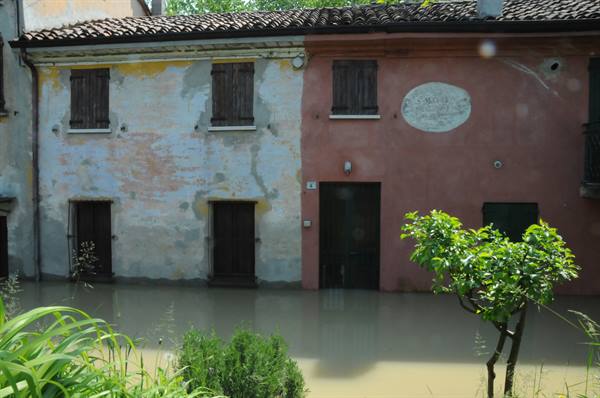 Old pink and white plastered houses flooded by brown water, maybe Borghetto sul Mincio