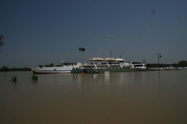 White boat moored on muddy swollen river under grey skies
