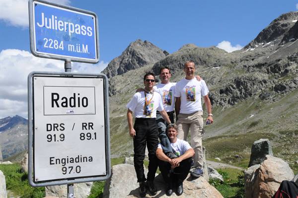 Four men in white shirts by the Julierpass sign, 2284 meters