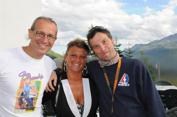 Three smiling friends posing together, mountains and clouds in the background