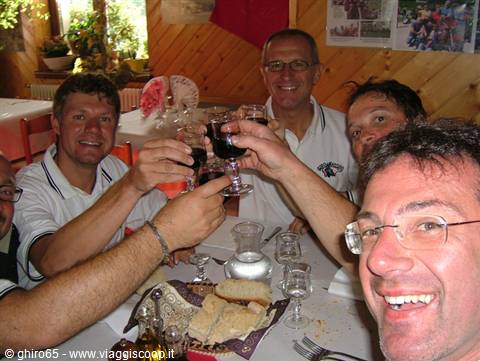 Group of friends toasting with red wine glasses in wooden trattoria