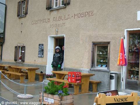 Boy in helmet exits the Gasthaus Albulahospiz in front of wooden tables