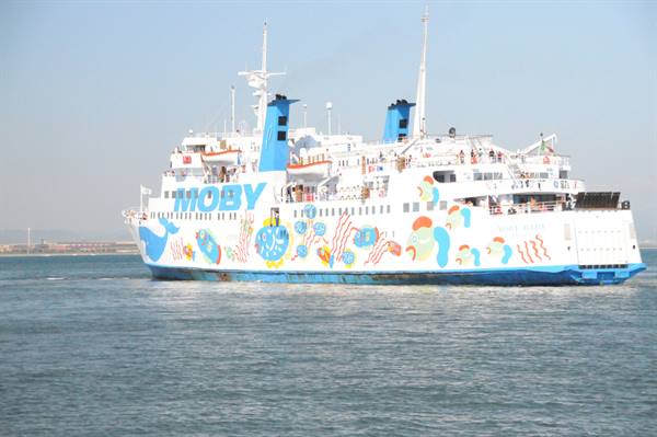White Moby ferry with colorful painted decorations sails on calm sea under clear sky