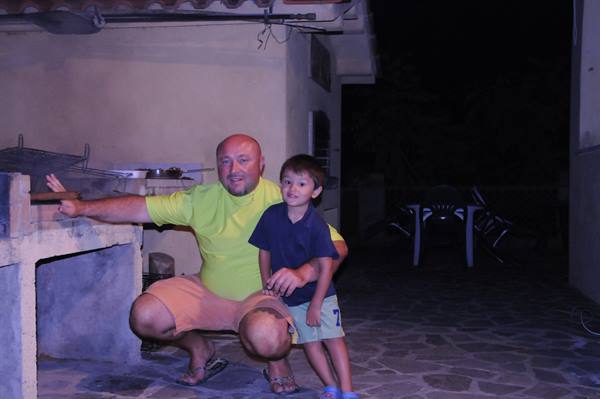 Man and child beside the stone barbecue in a courtyard at night