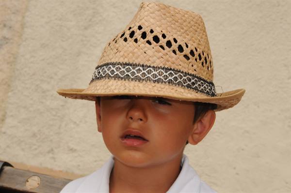 Child wearing a woven straw hat in front of a light wall