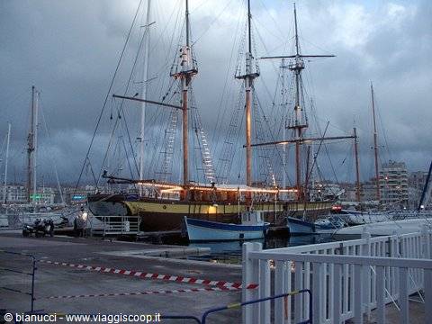 Three-masted tall ship moored in the marina among boats and docks
