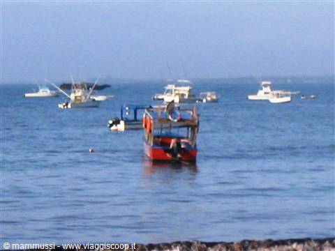 Fishing boats anchored offshore, red boat with engine in the foreground