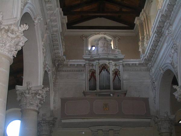Old pipe organ on baroque balcony inside a church with carved columns