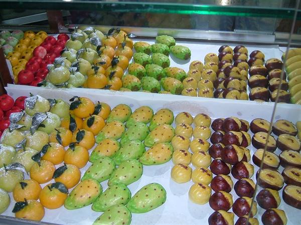 Pastry shop display of colorful marzipan frutta martoriana sweets