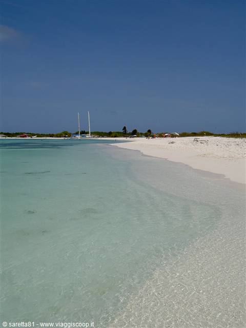 Clear turquoise water and white sand, a catamaran anchored near the shore