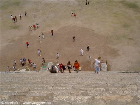 Tourists gathered on the dirt plaza seen down Teotihuacan's steep stone steps