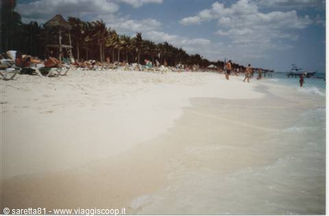 White sand beach with palm trees, umbrellas and tourists along the shore