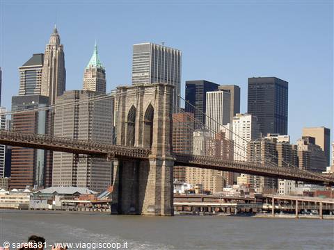 Brooklyn Bridge stone towers over East River, Manhattan skyscrapers behind