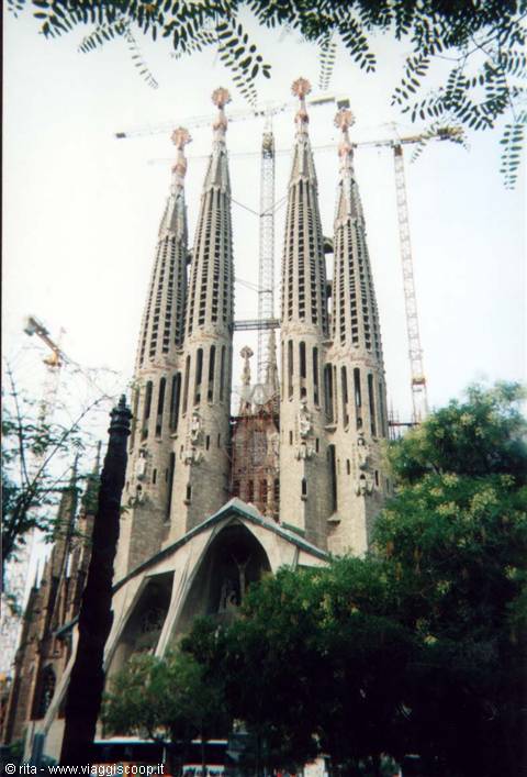 The Sagrada Família towers in Barcelona among cranes and greenery