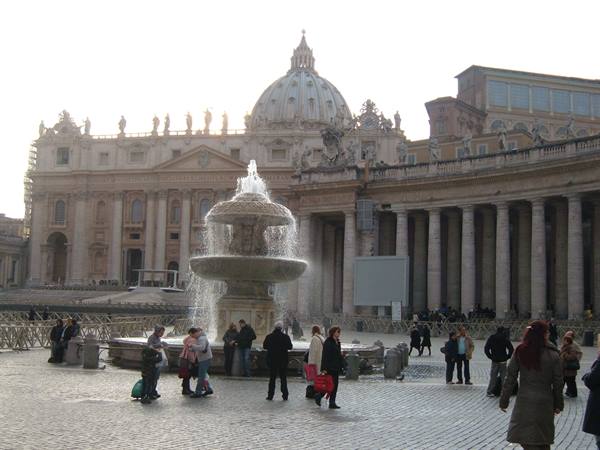 Tourists around the fountain in St. Peter's Square, Bernini's dome behind