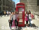 Tourists posing beside a red telephone box on a London street