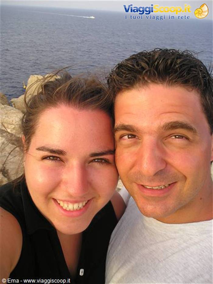 Smiling couple taking a selfie above rocky cliffs and open sea