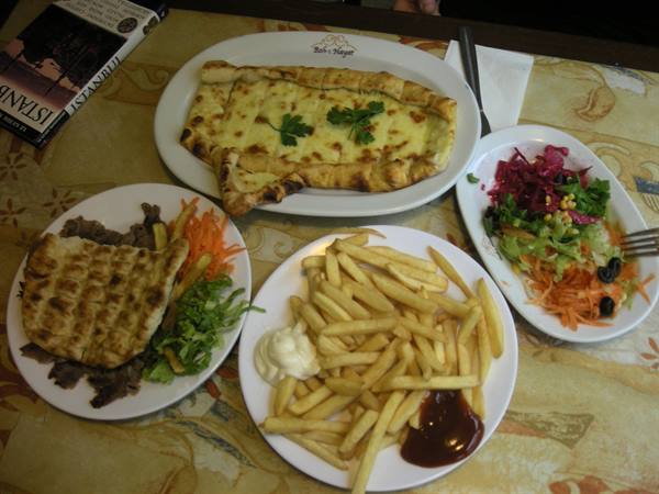 Turkish cheese pide with fries, salad and meat plates on a table, Istanbul guidebook