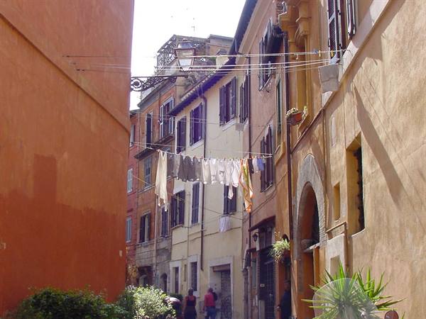 Laundry strung between ochre buildings on a narrow street, people walking