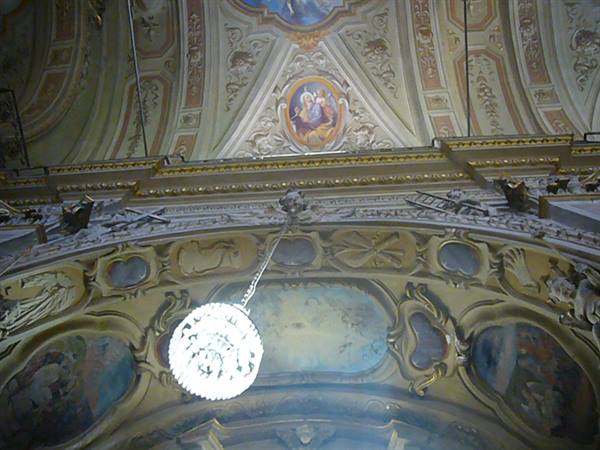 Baroque church ceiling with frescoes, gilded stucco and lit glass chandelier
