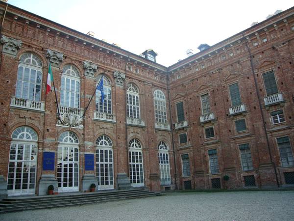 Courtyard of Reggia di Venaria Reale, brick facade with Italian and European flags