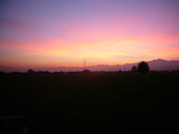 Pink and purple sky over dark fields and distant mountains