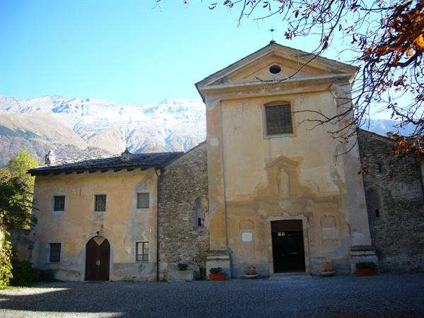 Old ochre church and stone houses, snowy mountains rising behind