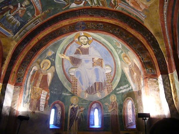 Fresco of Christ enthroned inside a medieval church lit by lamps