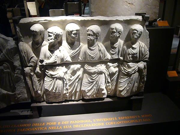 Marble relief of hooded figures in procession, exhibited in a museum